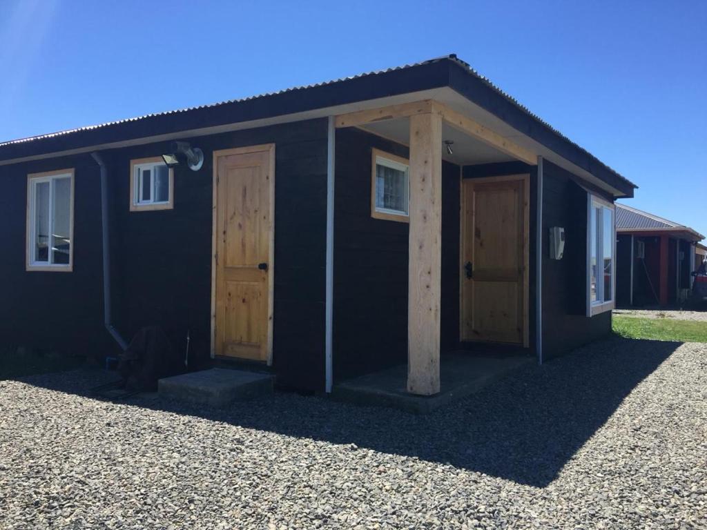 a black building with two doors on the side at Cabañas Tinajas hidromasaje Chanlelfu in Puyehue