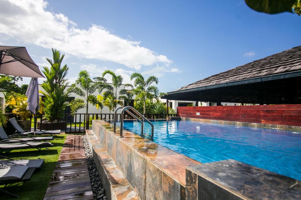 a swimming pool at a resort with chairs and an umbrella at Bronbella Villa Residence in Paramaribo