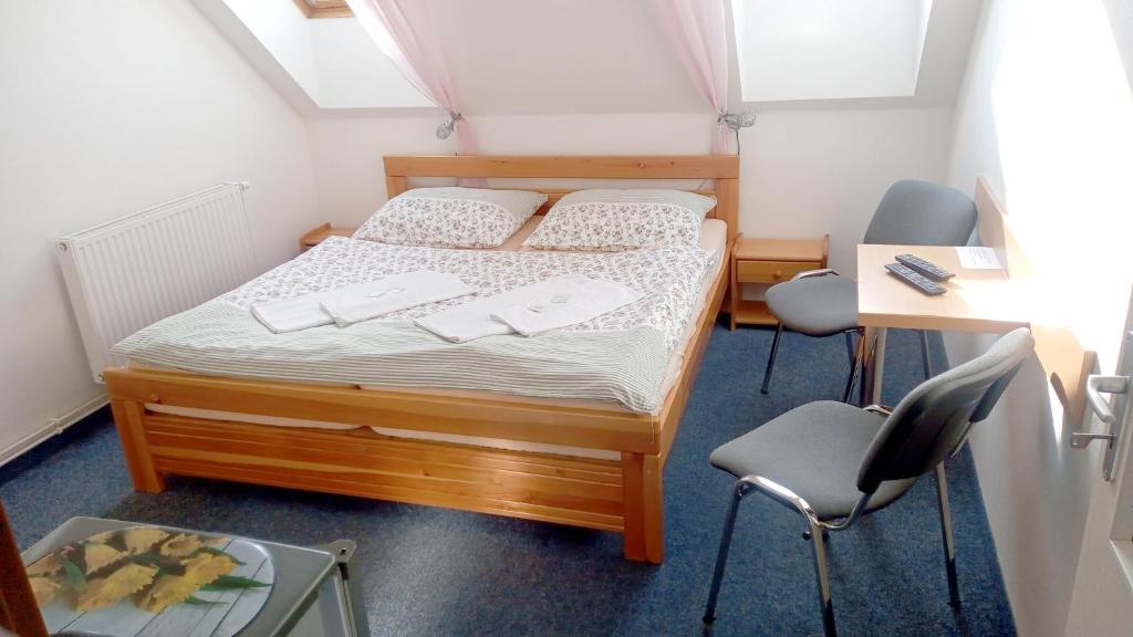 a small bedroom with a bed and two chairs at Penzion Pristav in Lipno nad Vltavou