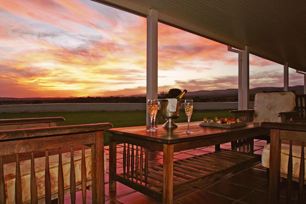 einen Tisch auf einer Veranda mit Gläsern Wein in der Unterkunft River Bend Lodge in Addo