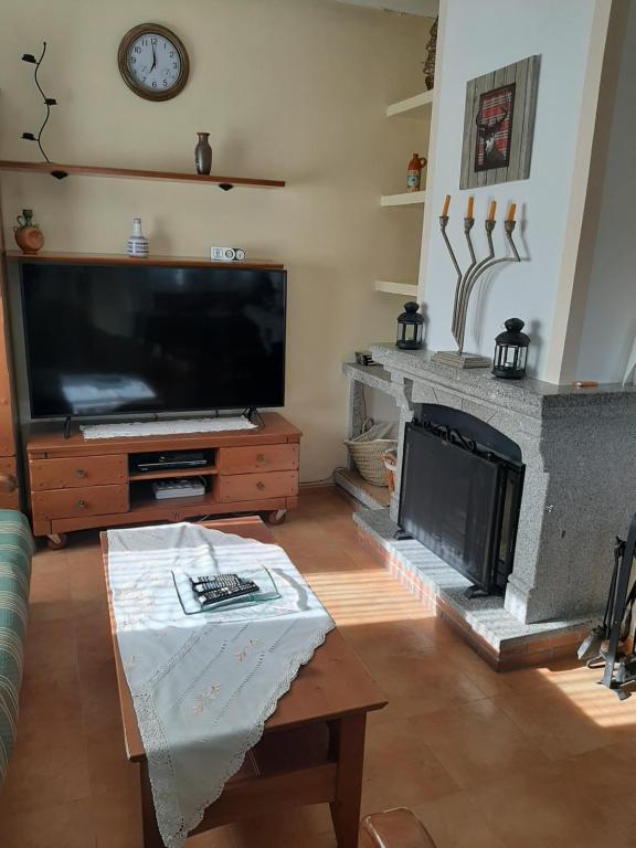sala de estar con TV grande y chimenea en Los Campos, en Padiernos