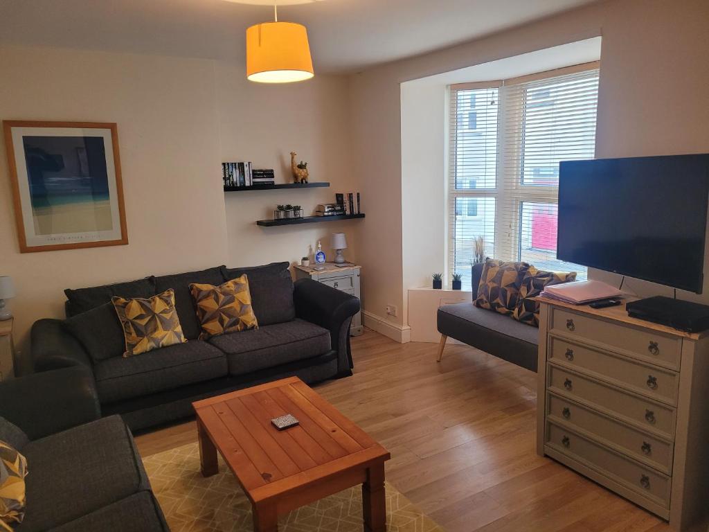 a living room with a couch and a flat screen tv at Large 5 bed town-centre home close to the beach, sleeps 9 in Aberystwyth