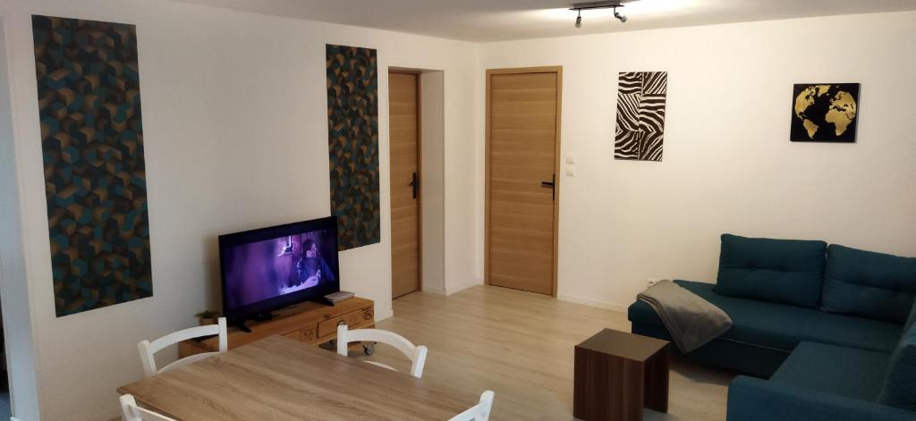 a living room with a blue couch and a tv at Maison à la campagne,à Saint-amand, Pas-de-Calais in Saint-Amand