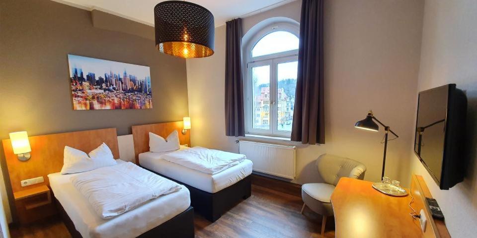 ein Hotelzimmer mit 2 Betten, einem Schreibtisch und einem Fenster in der Unterkunft Hotel Friedensbruecke in Greiz