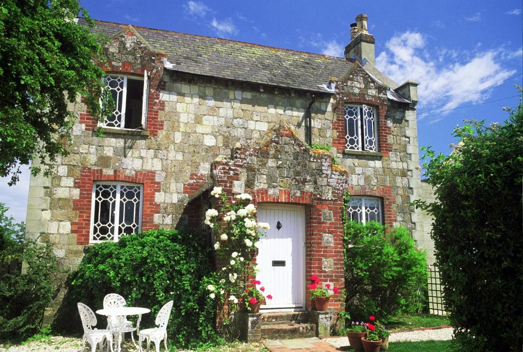 Casa de ladrillo con puerta blanca, mesa y sillas en Spire Cottage, en Chichester