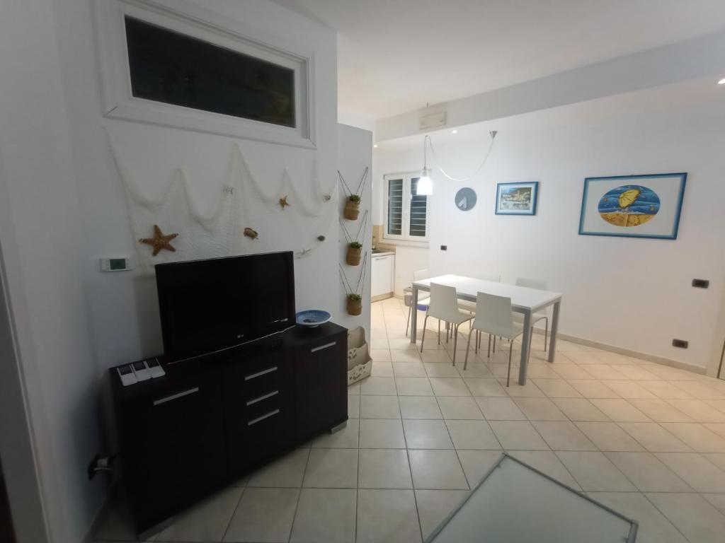 Il comprend un salon doté d'une télévision et d'une table avec des chaises. dans l'établissement Appartamento sul Corso, à Porto Recanati
