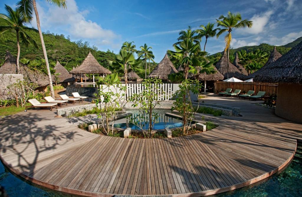 a resort with a wooden deck and a swimming pool at Constance Ephelia in Port Glaud
