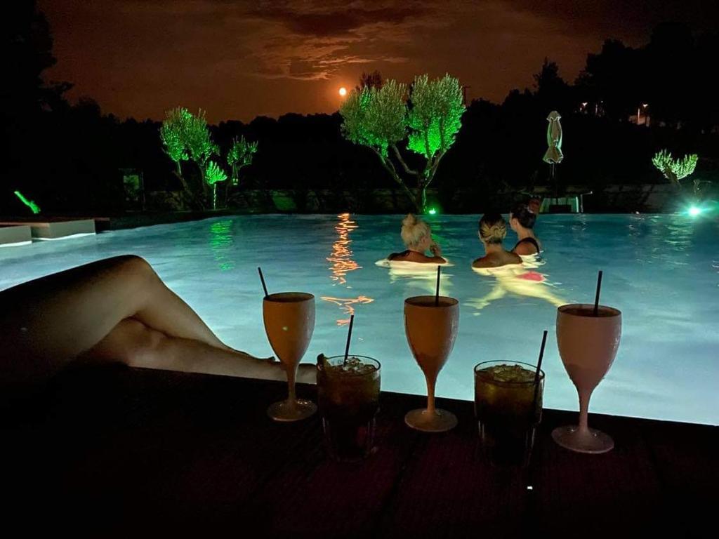 um grupo de pessoas a nadar numa piscina à noite em Sani Woods Studios & Apartments em Sani Beach