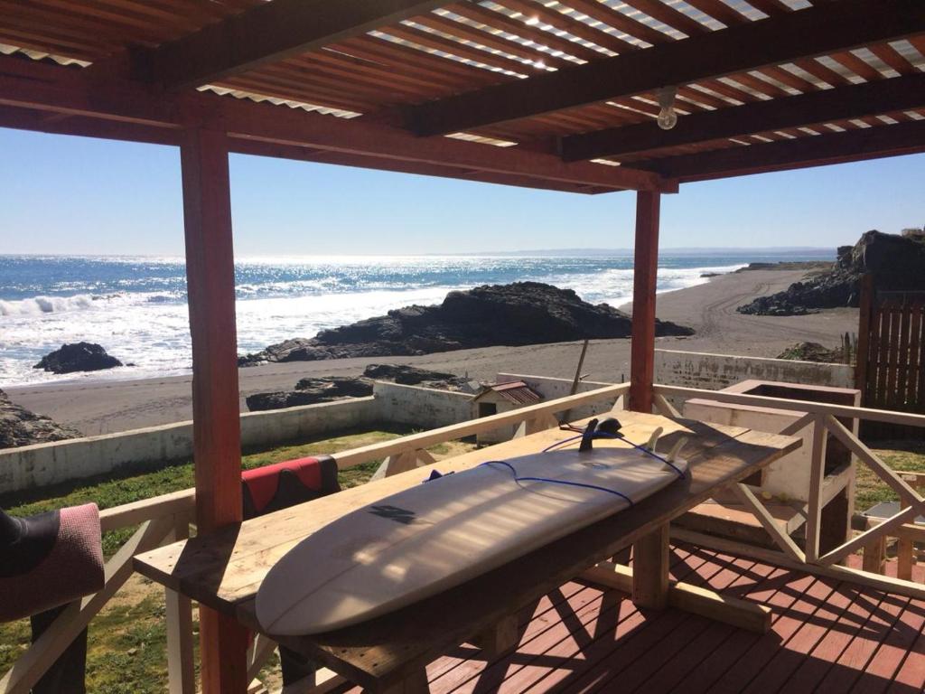 une planche de surf assise sur une table en bois sur une plage dans l'établissement Curanipe: primera linea de playa., à Curanipe