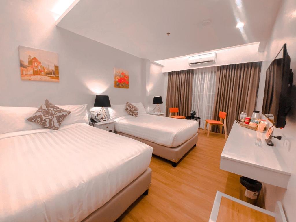 a hotel room with two beds and a desk at Via Appia Tagaytay in Tagaytay
