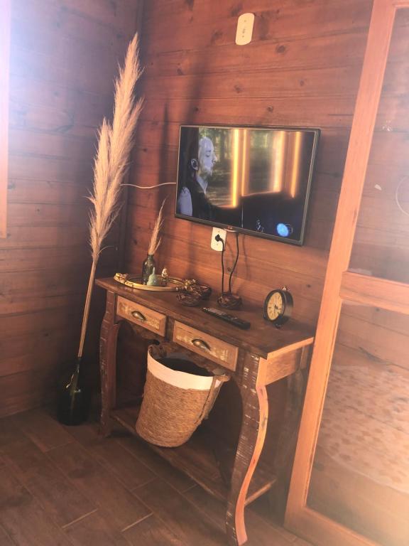 une table en bois avec une télévision fixée au mur dans l'établissement Chalé Recanto Verde dos Canyons, à Praia Grande
