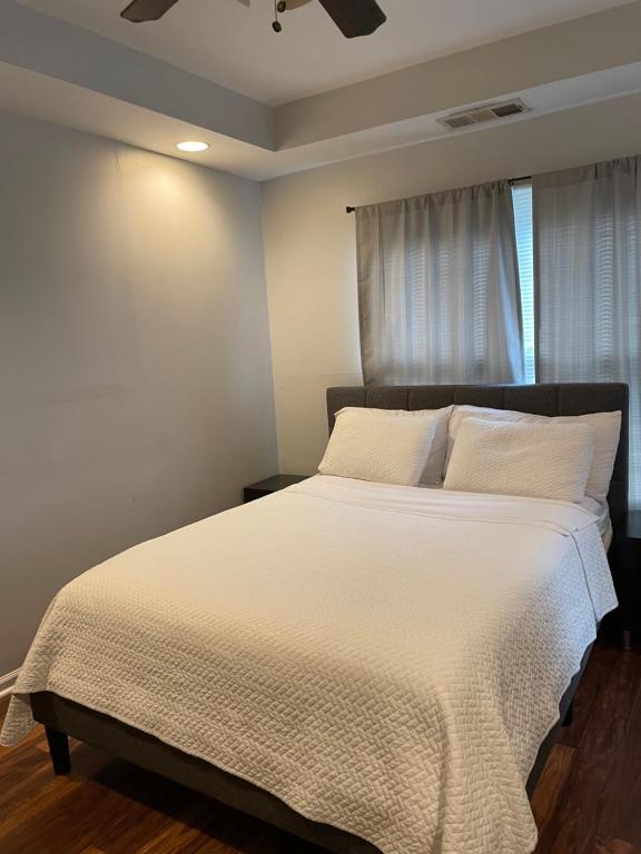 een slaapkamer met een bed met witte lakens en een raam bij A Room for You! in Atlanta