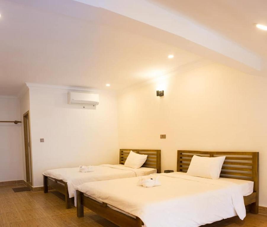 1 dormitorio con 2 camas con sábanas blancas en TWIN HOME Guesthouse en Kampot