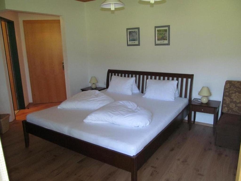 1 dormitorio con 1 cama con sábanas y almohadas blancas en Room in Apartment - Ferienhaus Kahr Appartment Rosbrand en Höggen