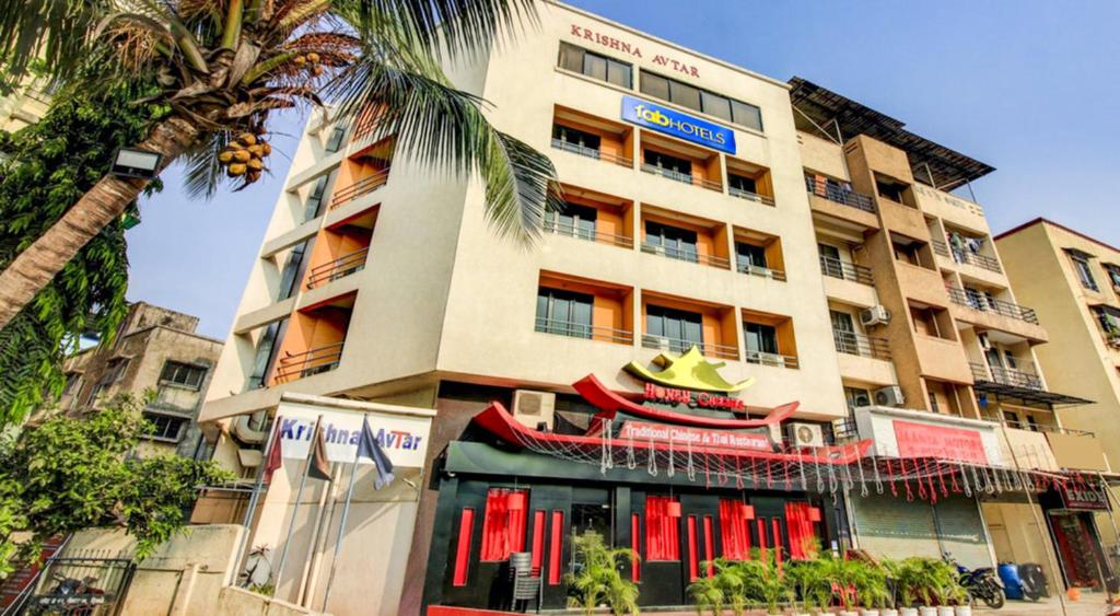un edificio alto con una palmera delante de él en Hotel Krishna Avtar, en Navi Mumbai