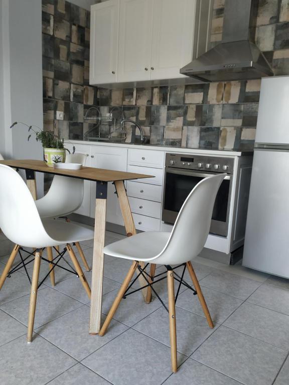eine Küche mit einem Holztisch und 2 weißen Stühlen in der Unterkunft Sweet house 64B in Vrachati