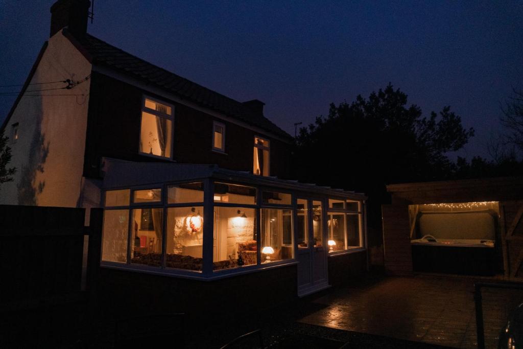 a house at night with lights in the windows at Hot Tub Pet Friendly Luxury Cosy Cottage, Near Withernsea and Patrington in Welwick