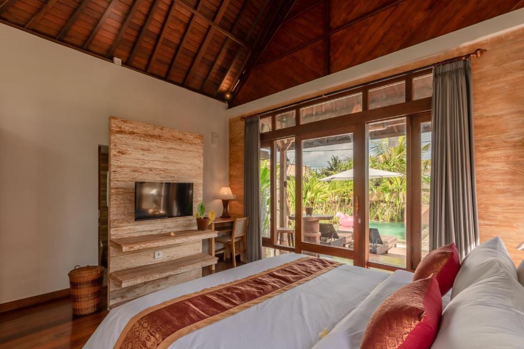 a bedroom with a bed and a tv and a patio at Sridewi Villas Ubud in Ubud