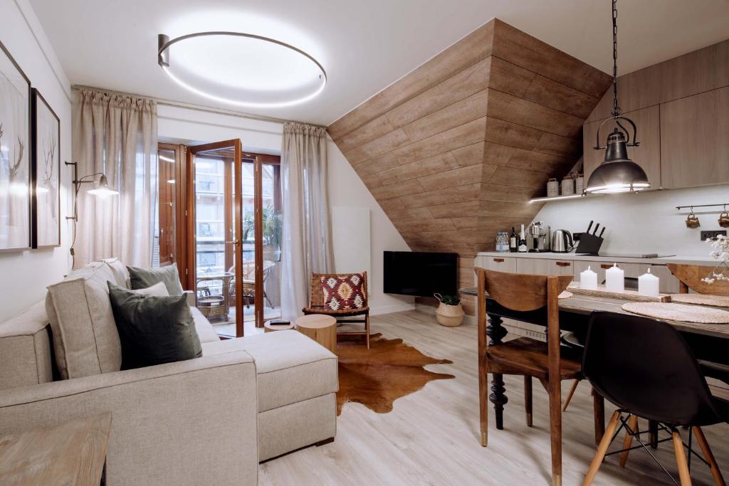 - un salon avec un canapé et une salle à manger dans l'établissement Diament Apartamenty Mozaika w Centrum z balkonem, à Zakopane