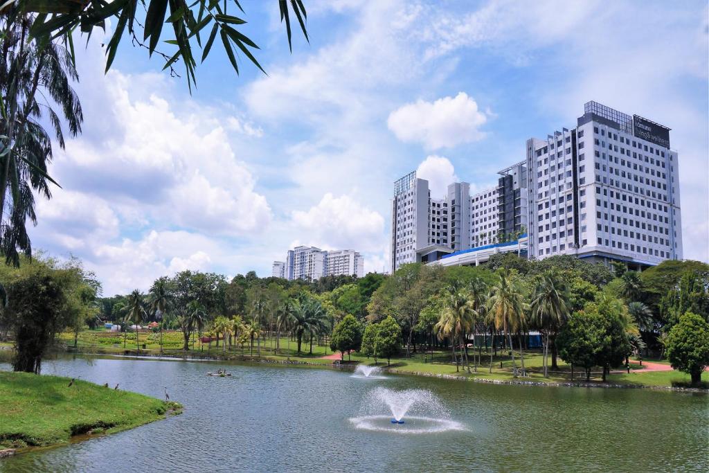 a fountain in a pond in a park with tall buildings at Hotel Komune Living & Wellness Kuala Lumpur in Kuala Lumpur