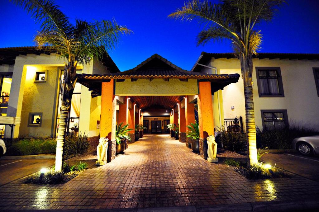 a hallway leading to a house with palm trees at Villa Bali Luxury Guesthouse in Bloemfontein