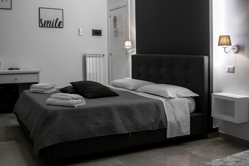a black and white bedroom with a bed with towels on it at Aurora Luxury Rooms in Naples