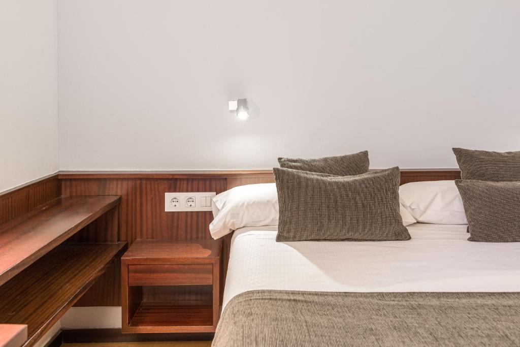 1 dormitorio con 2 camas y pared de madera en Hotel Emporda, en Figueres