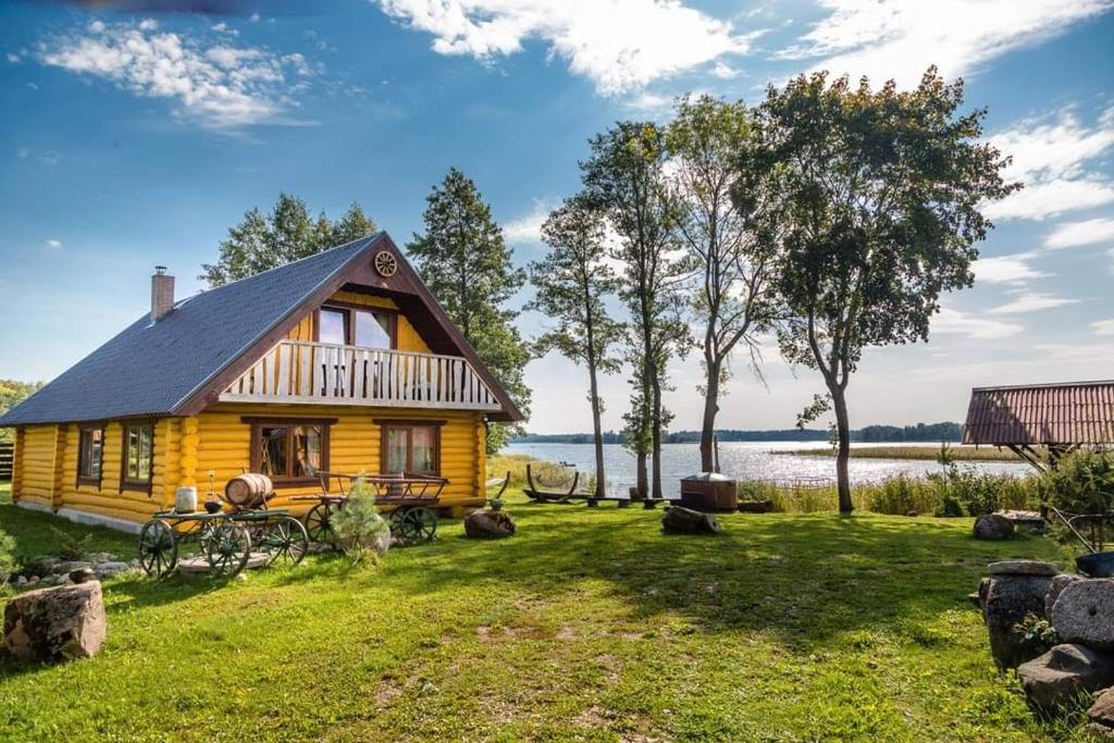 eine Blockhütte mit einem See im Hintergrund in der Unterkunft Saullēkti ozolos pie Ežezera in Ezernieki