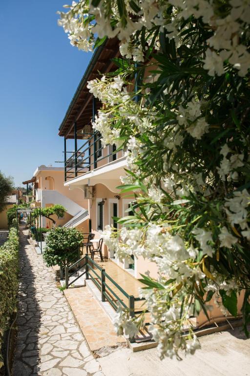 ein Gebäude mit weißen Blumen davor in der Unterkunft Lora Apartments & Studios with Balcony in Ipsos Corfu in Ýpsos