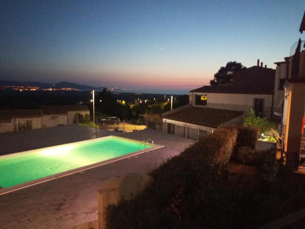 a swimming pool on the side of a house at night at Superbe appartement dans petite résidence . in Badesi