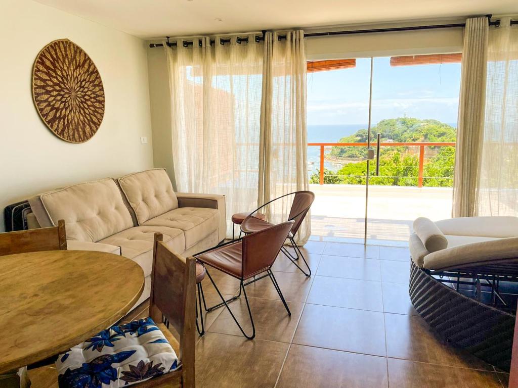 un soggiorno con un divano e un tavolo di Pouso do Sol - Apartamento com Vista Panorâmica em Morro a Morro de São Paulo
