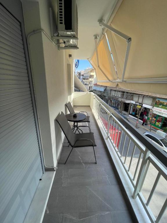 balkon z 2 krzesłami i stołem w budynku w obiekcie LA Larissa Luxury Apartments Peneus w mieście Larisa