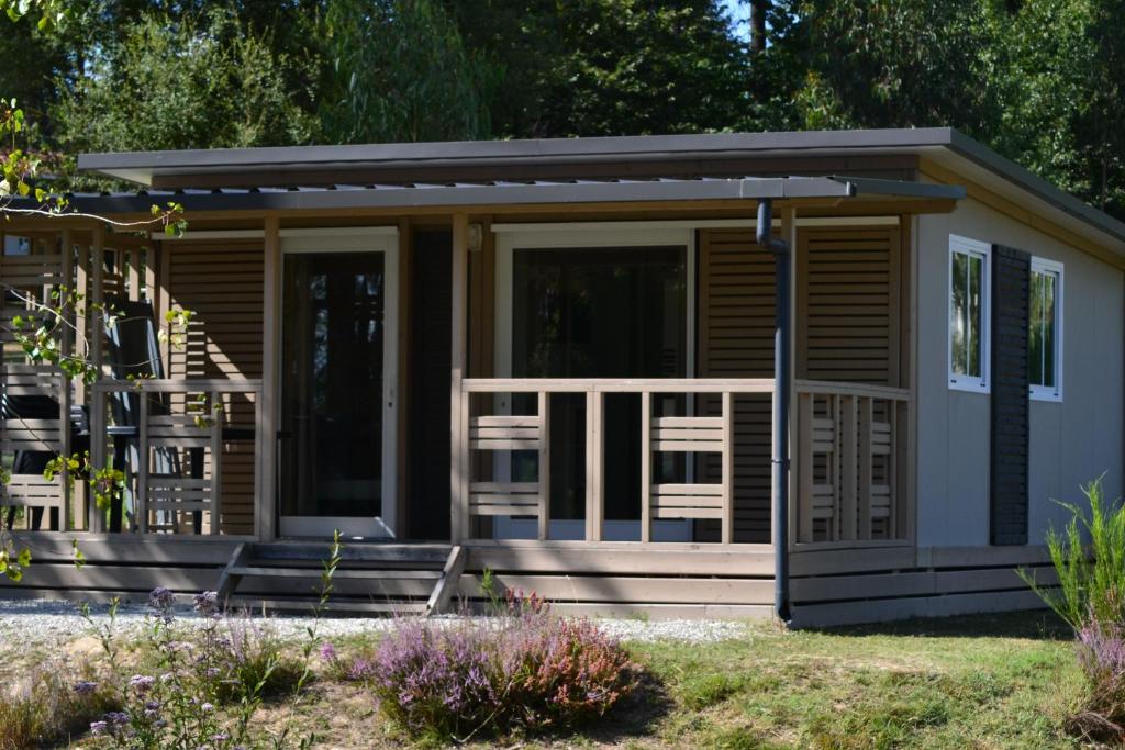 ein kleines Haus mit einer Veranda und einer Terrasse in der Unterkunft DOMAINE des GRANDS PINS in Tamniès