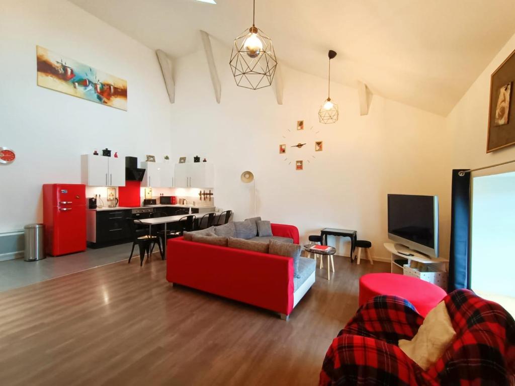 a living room with a red couch and a tv at Superbe appartement type loft en duplex rue Buat in Châlons-en-Champagne