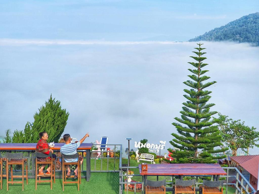 two people sitting at a table with a christmas tree at Mhork Buri Resort in Khao Kho
