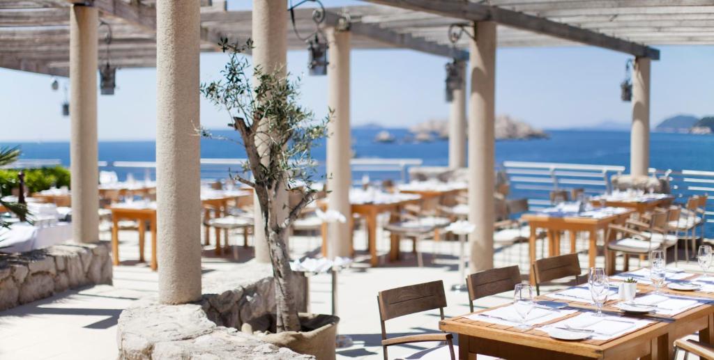 a restaurant with tables and chairs with the ocean in the background at Hotel Dubrovnik Palace in Dubrovnik