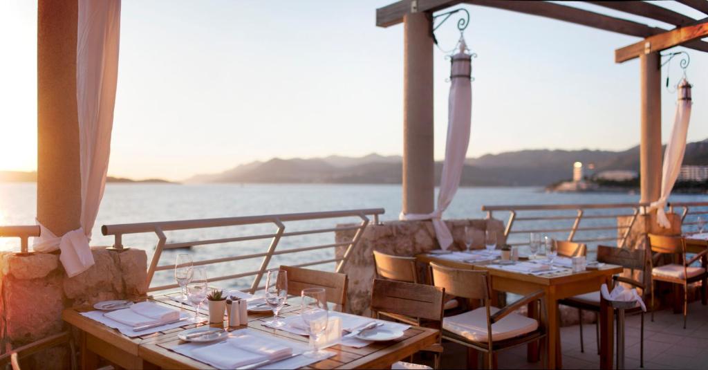 a restaurant with tables and chairs and the water at Hotel Dubrovnik Palace in Dubrovnik