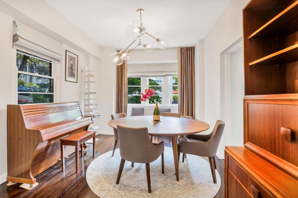 a dining room with a table and a piano at Premium Double Bay 3 bedroom apartment in Sydney