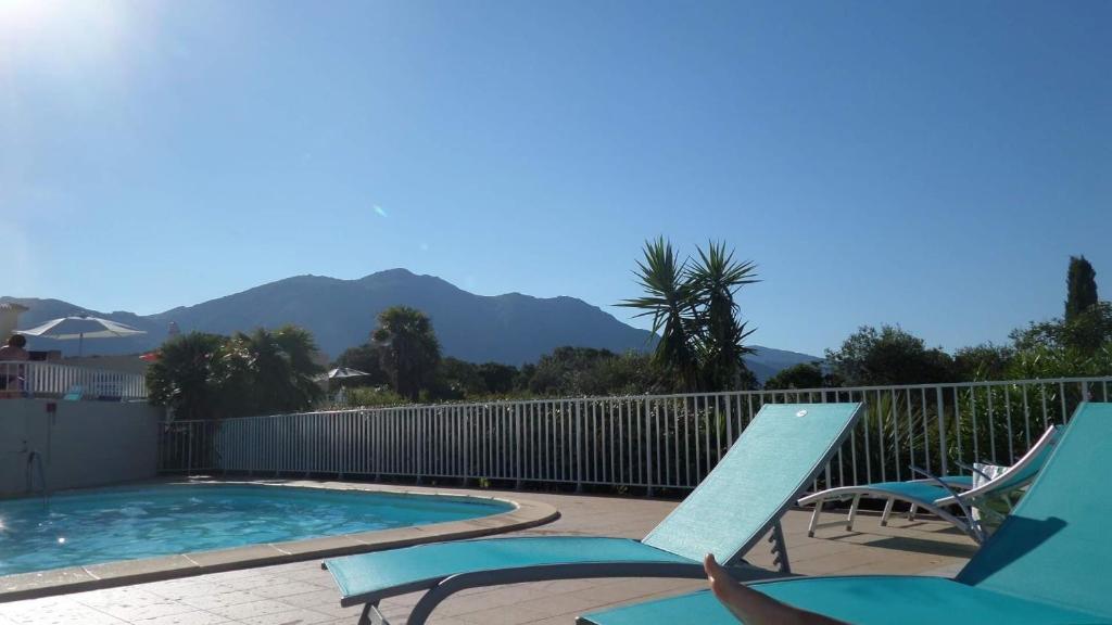 a swimming pool with two lawn chairs next to a swimming pool at Corsiani Di Prunete, mer, tennis, piscine in Cervione