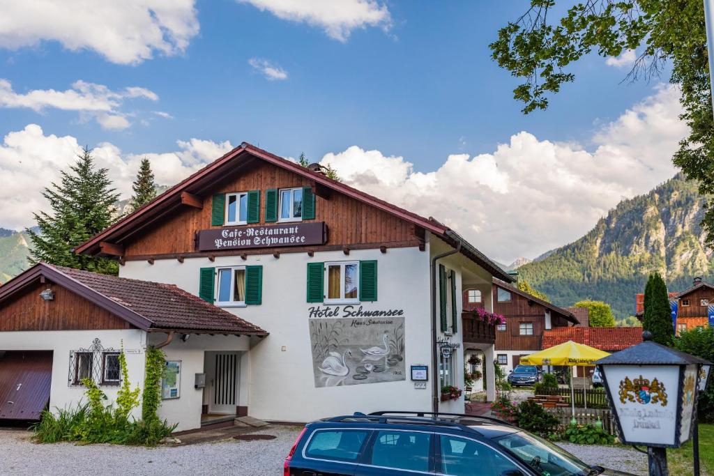 un bâtiment avec une voiture garée devant lui dans l'établissement Hotel Pension Schwansee, à Schwangau