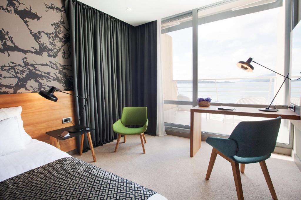 a hotel room with a bed and a desk and chairs at Hotel Dubrovnik Palace in Dubrovnik