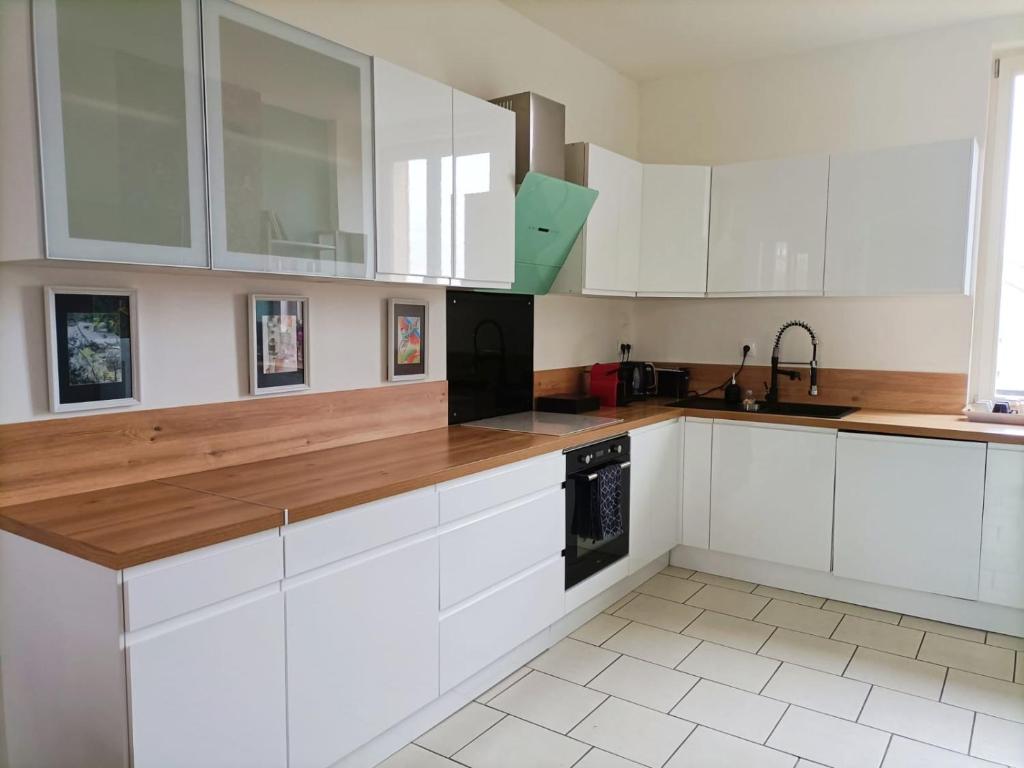 een keuken met witte kasten en een houten aanrecht bij Magnifique duplex 3 chambres proche centre-ville et gare Chemin du Barrage in Châlons-en-Champagne