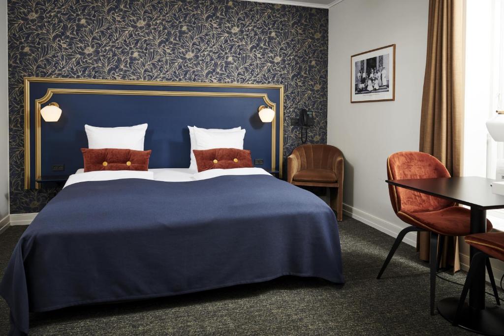 a hotel room with a blue bed and chairs at Hindsgavl Slot in Middelfart