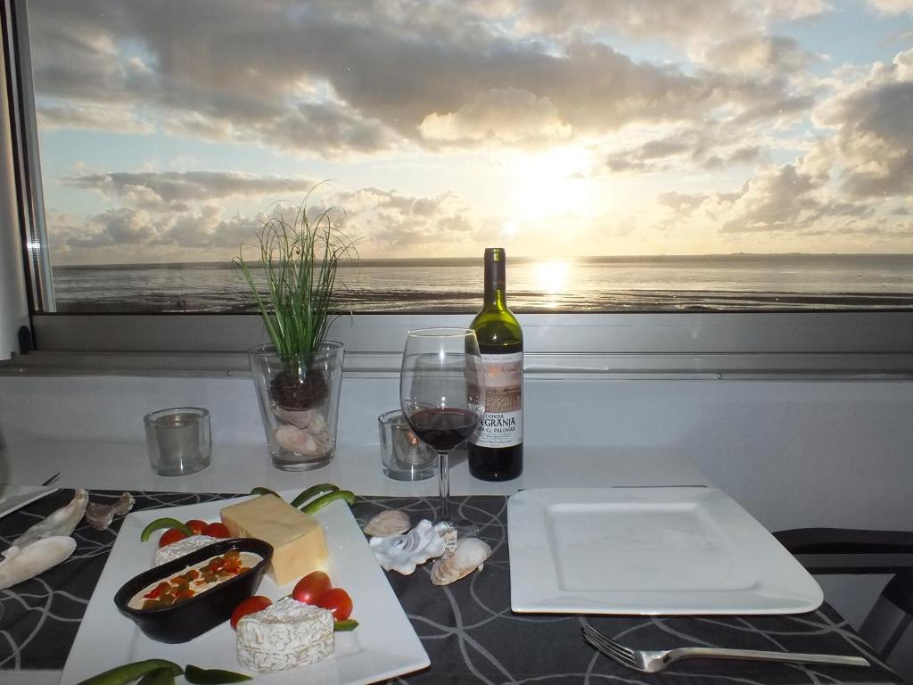 einen Tisch mit einer Flasche Wein und einem Teller Essen in der Unterkunft Watten-Blick 2 in Cuxhaven
