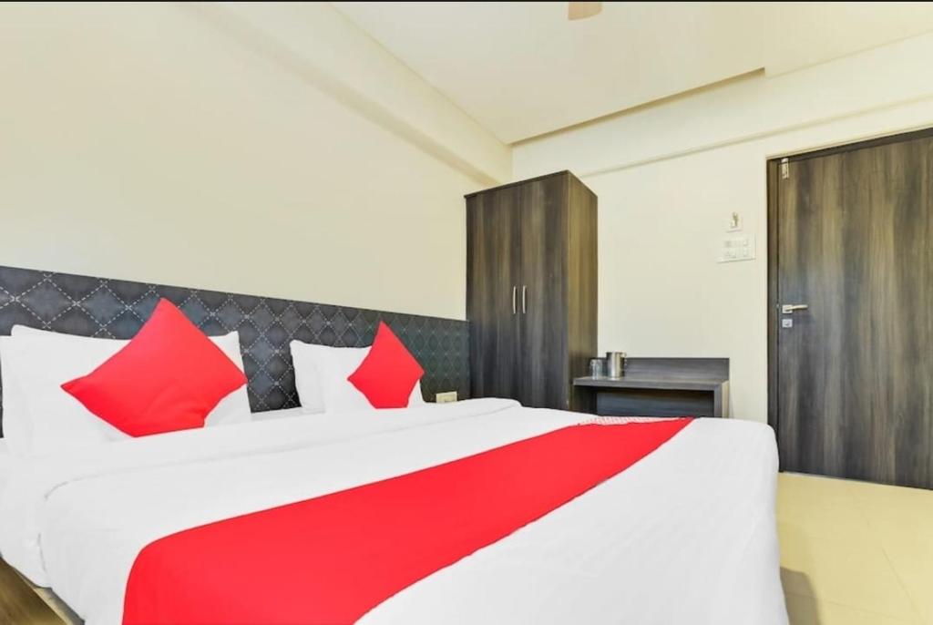 una cama roja y blanca con almohadas rojas en un dormitorio en HOTEL SHARADA INTERNATIONAL, en Thane
