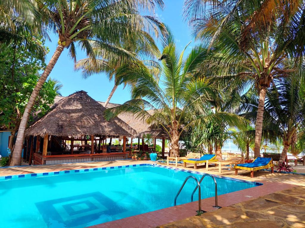 a swimming pool with palm trees and a resort at Santa Maria Coral Park in Pongwe