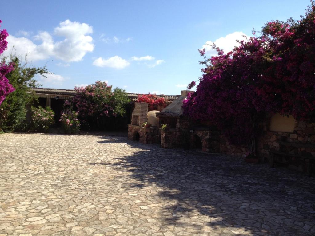 een stenen loopbrug met bloemen en een stenen muur bij Il Ruscello in SantʼAnna Arresi