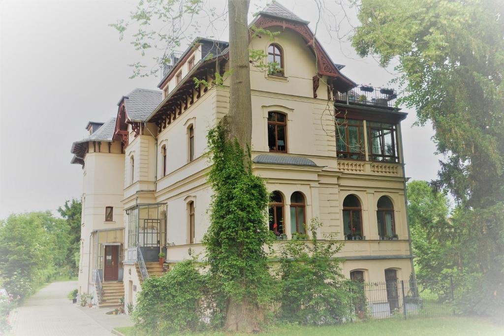 uma casa grande com uma árvore em frente em Villa Moser - Ferienwohnung mit Terrasse em Gera