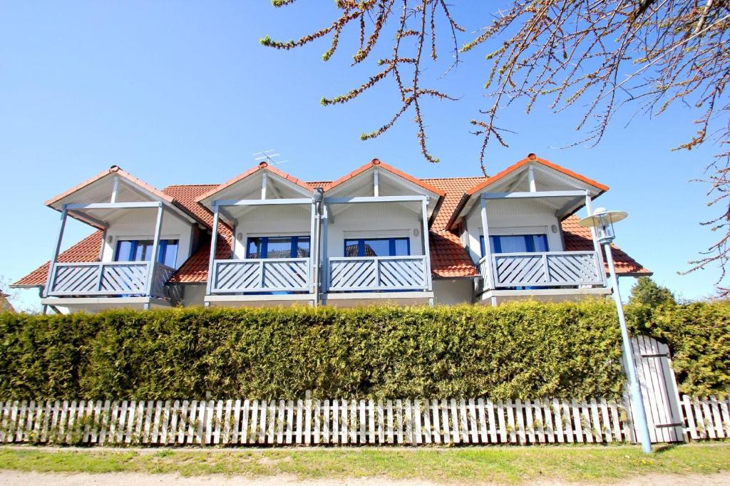 a house with a white fence in front of it at gemütliche Ferienwohnung in Hafennähe - FeWos am Hochzeitsberg FeWo 10 in Breege