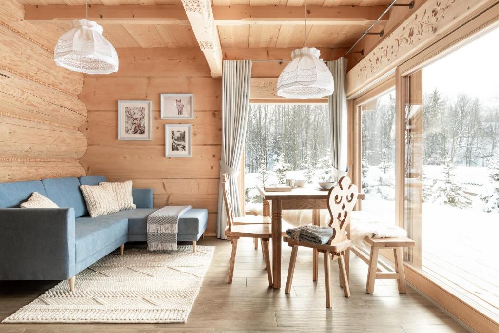 a living room with a blue couch and a table at Śnieżna Dolina - Sobiczkowa Bór Luxury Chalets in Kościelisko